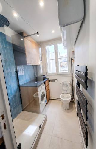 Salle d'eau rénovée, douche à l'italienne, faïence bleue et sèche serviettes.