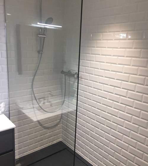 Douche rénovée avec carrelage métro blanc et colonne de douche moderne.