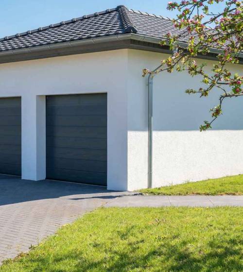 garage blanc avec un grand jardin vert