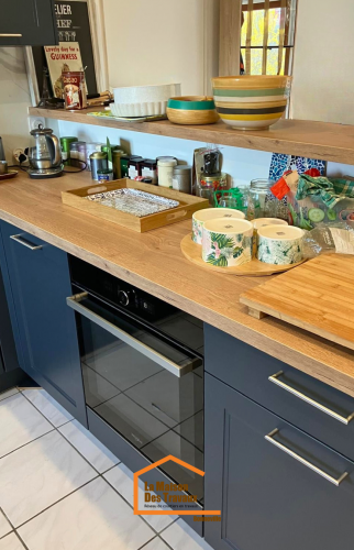 Cuisine moderne avec meubles bleu nuit, plan de travail en bois clair et étagères ouvertes avec accessoires déco.