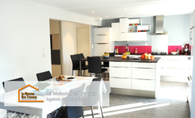 Vue d’ensemble de la cuisine rénovée avec un îlot central accueillant et une table à manger à proximité pour plus de convivialité.