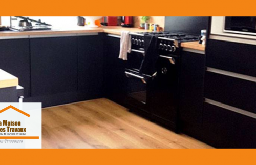 une cuisine noire mate sublimée par des touches de bois clair pour réchauffer l’ensemble, un plan de travail épuré, et un électroménager parfaitement intégré. 