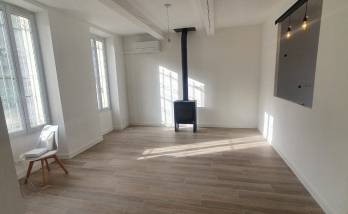 Salon rénové avec poêle à bois et ouverture cuisine