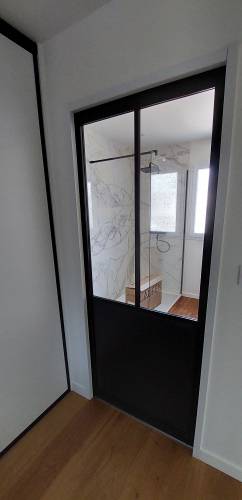 Porte coulissante type verrière atelier, salle de bain en arrière plan