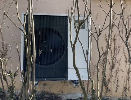 Installation extérieure, discrète, derrière la maison et camouflée par les arbustes