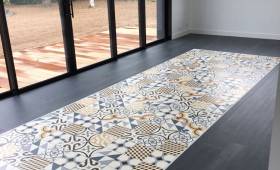 Vue d'ensemble d'une pièce de vie avec tapis de sol en carreaux de ciment et grandes baies vitrées à Courcelles-lès-Lens.