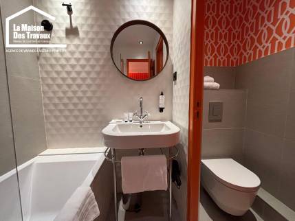 WC suspendu blanc installé dans une pièce d'eau avec rappel du papier peint orange.