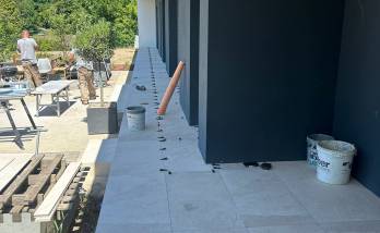 Pose d’un carrelage extérieur grand format pour la création d’une terrasse contemporaine autour d’une maison à Voiron.