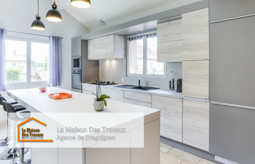 Une perspective qui montre la continuité entre la cuisine et le salon, créant un espace ouvert et harmonieux. Le choix des matériaux et des couleurs permet une intégration parfaite avec le reste de la maison.