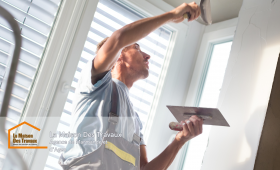 Un artisan en plein travail sur un mur, appliquant un enduit avec précision pour lisser les imperfections. 