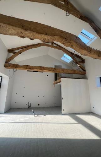 Valorisation des volumes et des poutres anciennes dans cette rénovation complète de grange.