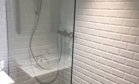 Douche rénovée avec carrelage métro blanc et colonne de douche moderne.