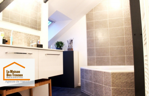 Salle de bain moderne sous combles rénovée à Vesoul. Un espace optimisé avec baignoire, double vasque et lumière naturelle.