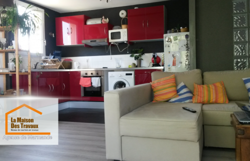 Une vue d’ensemble de la cuisine et du salon, où le parquet imitation bois apporte chaleur et modernité à l’espace.