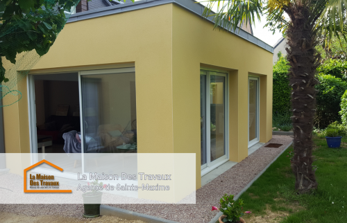 Vue intérieure de l'extension avec de grandes baies vitrées, baignant l’espace de lumière naturelle et offrant une vue apaisante sur le jardin.