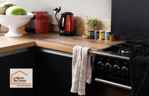 Espace cuisson d'une cuisine contemporaine noire et bois près d'Aix-en-Provence, avec électroménager intégré et implantation pensée pour un usage fluide et convivial.