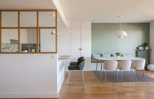 Table à manger blanche ovale et banquette contre un mur vert