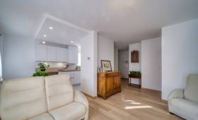 Le salon en premier plan, et la cuisine ouverte derrière