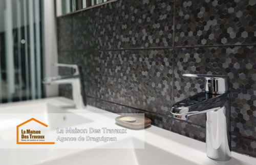 Un meuble sous-vasque suspendu moderne et pratique, avec un mur en carrelage mosaïque pour une touche élégante.