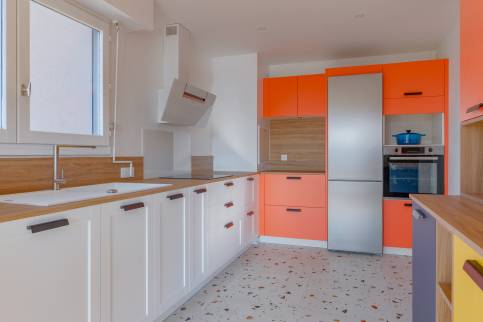 Cuisine multicolore dans un appartement de Lyon quai de Saône : vue sur le linéaire côté fenêtre et les armoires de rangement