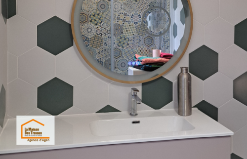Installation d’un meuble vasque suspendu avec miroir rond et carrelage hexagonal dans une salle de bain rénovée entre Agen et Boé.