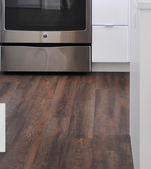 Un sol en parquet stratifié imitation bois foncé posé dans une cuisine moderne à Agen, par La Maison Des Travaux. Élégance et durabilité au rendez-vous.