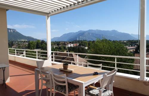 Pergola bioclimatique avec lames ouvertes sur une terrasse d’appartement à Voiron, offrant une vue dégagée sur les massifs du Pays Voironnais.