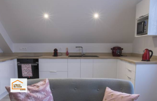 Cuisine moderne réalisée à Quimper avec mobilier blanc, plan de travail effet bois et implantation optimisée. Une rénovation intérieure accompagnée par La Maison Des Travaux Quimper.