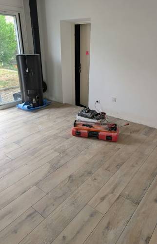 Pose d’un nouveau revêtement de sol effet bois dans la pièce de vie d’une maison en rénovation à Voiron.