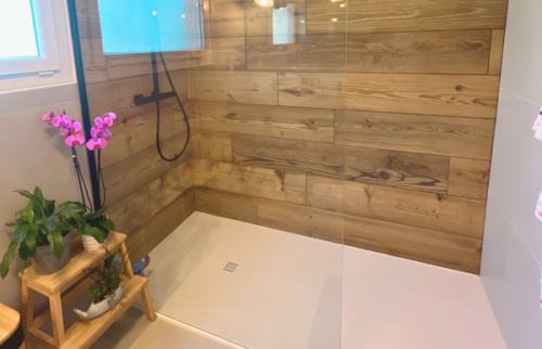 Détail de la douche moderne avec paroi vitrée et robinetterie noire.