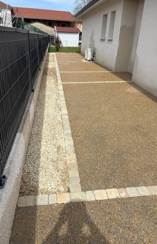 Cour en béton désactivé à Saint-Cassien avec bordures en pavés et finition en gravier.