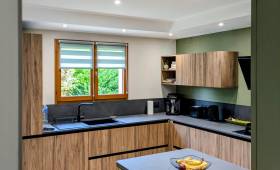 Vue d'ensemble de la cuisine, avec une belle harmonie bois, vert sauge et noir