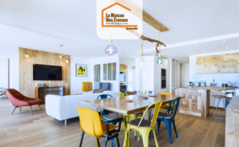 Pièce à vivre moderne en Haute-Savoie avec cuisine en bois clair, salle à manger colorée et salon ouvert – rénovation intérieure signée La Maison Des Travaux.