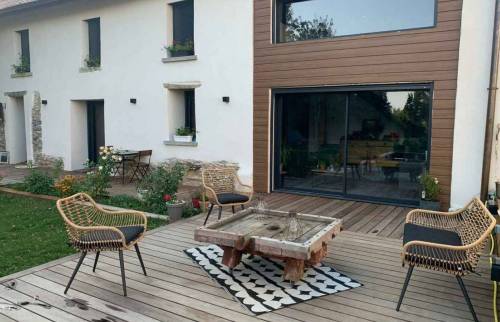 Aménagement extérieur finalisé avec terrasse bois sur-mesure devant une maison en pisé à La Côte-Saint-André : un véritable espace de vie convivial et chaleureux