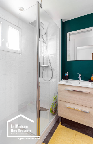 salle de bain vert de face avec lavabo en bois clair douche a l'italienne blanc 
