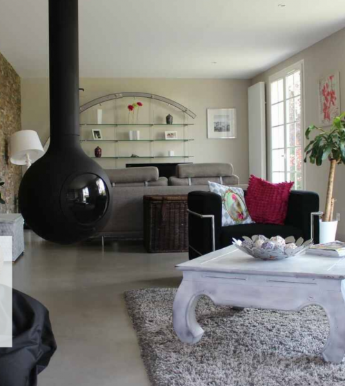 La photo met en avant un salon chaleureux et moderne, avec un poêle suspendu noir qui ajoute une touche contemporaine, et des ouvertures généreuses offrant une luminosité exceptionnelle 🌟.