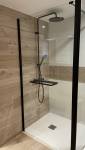 Carrelage imitation bois et robinetterie noire dans cette douche à receveur extra plat