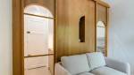 Espace de vie optimisé avec un canapé-lit et une paroi en bois clair