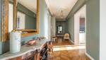 Rénovation à Saint-Cloud : Un miroir doré apporte une touche de luxe au couloir.