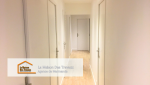 Un long couloir élégant aux murs blancs et aux portes assorties, qui met en valeur un parquet aux tons naturels. Ce couloir bien éclairé et épuré constitue un espace de transition agréable et fonctionnel, donnant un style moderne et raffiné à l'ensemble.