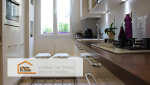 Les carreaux de ciment au sol et les éclairages intégrés sous les placards ajoutent une touche décorative et moderne à cette cuisine rénovée.