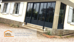Façade rénovée avec une avancée fermée, intégrant des baies vitrées modernes en aluminium noir.