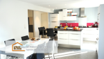 Vue d’ensemble de la cuisine rénovée avec un îlot central accueillant et une table à manger à proximité pour plus de convivialité.
