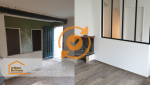   L'image montre l'espace avant rénovation, avec des murs sombres et vieillissants, un sol usé en carrelage et une séparation visuelle importante entre l'entrée et le salon