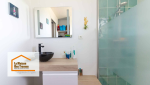 Focus sur le meuble de salle de bain suspendu, en bois clair, avec une vasque noire et un miroir rectangulaire. L’agencement soigné et minimaliste illustre parfaitement l’équilibre entre esthétique et fonctionnalité dans cette rénovation.