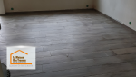 Le résultat après rénovation : un sol en carrelage imitation bois, chaleureux et intemporel, accompagné d’une verrière noire qui apporte une touche industrielle et élégante. 