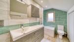 Dans la salle de bain, un éclairage blanc au plafond avec une source secondaire au dessus du lavabo