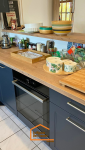 Cuisine moderne avec meubles bleu nuit, plan de travail en bois clair et étagères ouvertes avec accessoires déco.