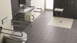 Douche de plain pied et WC avec poignée dans salle de bain PMR