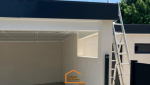 Construction d’un carport en Haute-Savoie avec structure maçonnée, toit plat moderne et finition noire – vue latérale avec échelle.